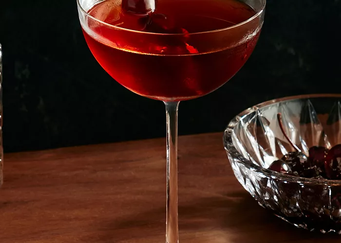 A glass of Baker's® Midnight Manhattan garnished with Cherry 