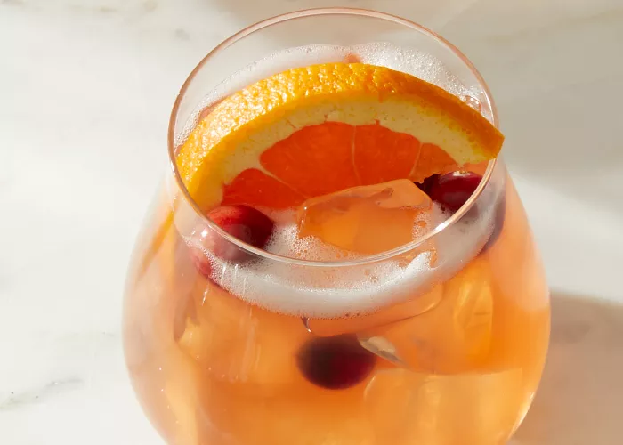 A glass of Pinnacle® Holly Jolly Punch garnished with Orange slice and Cranberries 
