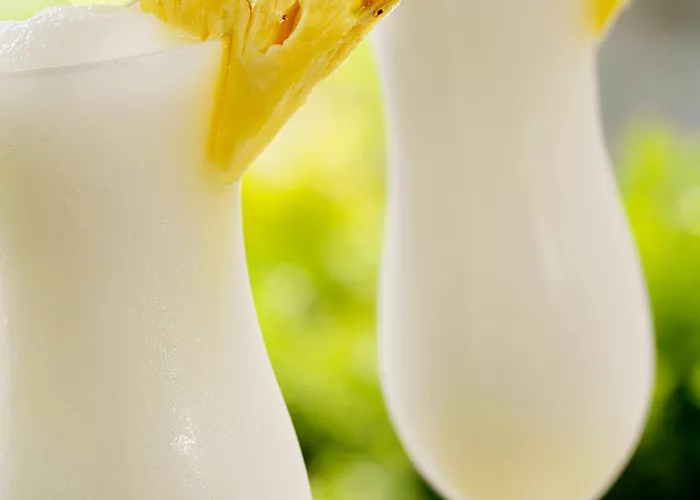 Two glasses of Cruzan® Colada garnished with pineapple slice and cocktail umbrella