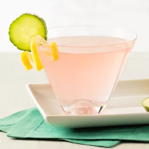 A glasses of Cucumber Watermelon Martini, garnished with cucumber and lemon peel twists on the rim of the glasses, are arranged in a white tray