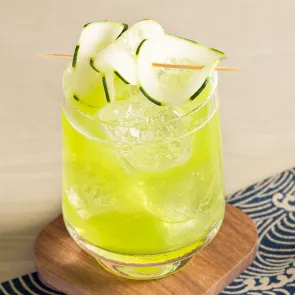 Glass of Cucumber Cooler garnished with cucumber slices on coaster