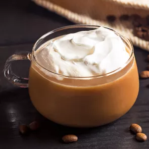 Cup of Kentucky Coffee garnished with whipped cream alongside coffee beans