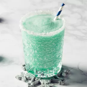 Glass of Blue Flurry rimmed with powdered sugar with straws on snowflake shaped coaster