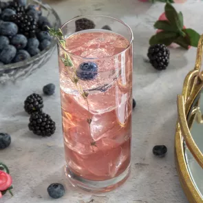 A glass of The Berry Thought of You garnished with  Blackberries, and Thyme Sprig