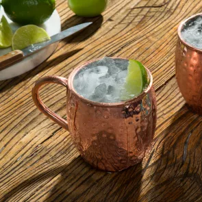 A copper cup of Bruxo® Mezcal Mule garnished with Lime Wedge