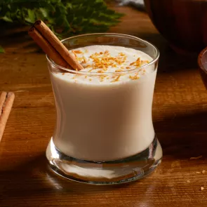 A glass of Cruzan® Coquito garnished with Cinnamon Stick and Shredded Coconut 