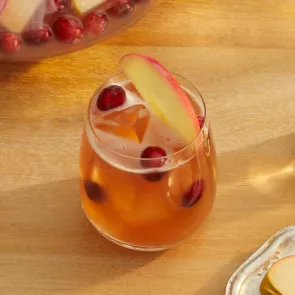 Glass of Cruzan® Cranberry Cider Punch garnished with apple slice and cranberries