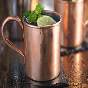 Bronze Cup of Blue Mule garnished with lime slice and mint leaves