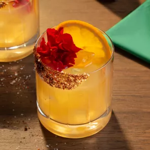 A glass of Don Francisco Margarita garnished with Orange Wheel and Edible Marigold 