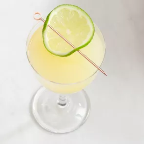 A glass of Gimlet garnished with lime slice 