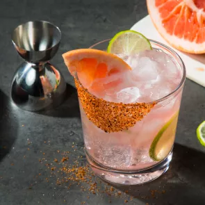 A glass of Hornitos® Paloma garnished with Grapefruit Wedge, Salt and Spice Rim and a chopped lemon