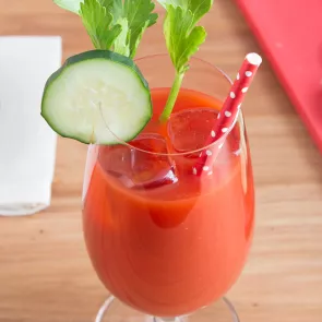 A glass of Skinnygirl® Bloody Mary garnished with Cucumber Slices , mint leaves and a straw