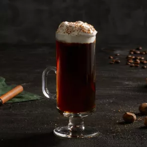 A glass of  Kilbeggan® Irish Coffee garnished with Whipped heavy cream and Grated Nutmeg