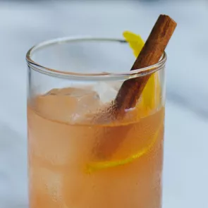 A glass of Laphroaig® Broadbay Sour, garnished with ice cubes, orange peel and cinnamon stick