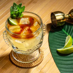 A glass of Mai Tai garnished with Mint Sprig and Lime Wedge 