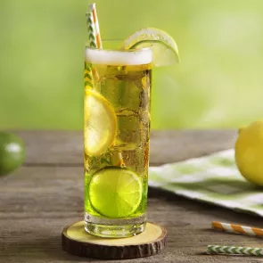 a glass of Green Eyed Ginger with limes and straws