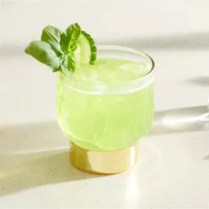 A glass of Midori® Pot of Gold garnished with cucumber and mint Basil leaves