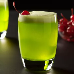 Glass of Fresh Midori® Sour garnished with a cherry.