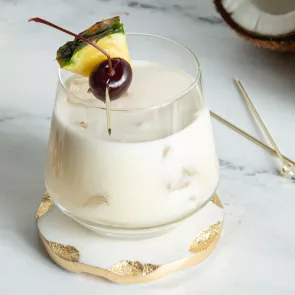 A glass of Piña Colada garnished with Pineapple Slice and Cherries 