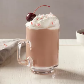 A glass of Pinnacle® Peppermint Hot Chocolate garnished with Whipped Cream and cherry 