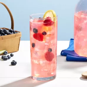 A glass of Pinnacle® Raspberry Lemonade garnished with Raspberries, Blueberries and Lemon Wheel