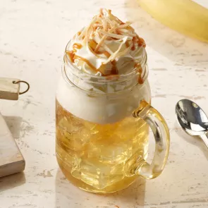 A glass of SQRRL® Top Banana garnished with Whipped Cream and toasted Coconut 