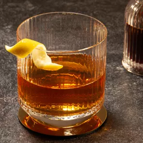 A glass of Sazerac garnished with lemon peel