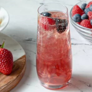 A glass of  Sparkling Berry Sangria garnished with Strawberries and Blueberries 