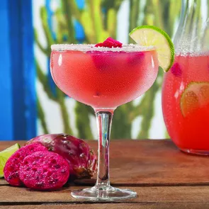 A glass of Prickly Pink Margarita garnished with crushed sugar and lemon slice on the rim of glass