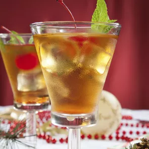 Two glasses of Spiced Cherry Sipper garnished with cherry and mint leaves