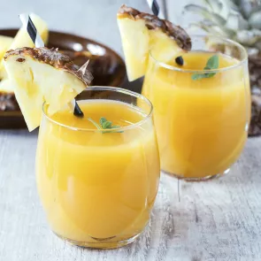 Two glass of Planter's Punch garnished with slice of pineapple on rim and a straws