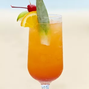 A Glass of Voodoo Hurricane garnished with crushed ice, cherry, orange, lemon, and fruit wedges.