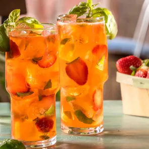 Glass of Basil Berry Mojito garnished with basil leaves and sliced strawberries