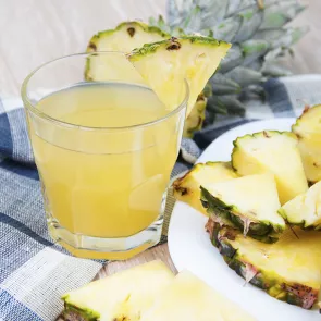 Glass of Pineapple Smash garnished with pineapple slice alongside some slices of pineapple