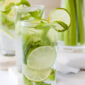 Glass of strawberry Basil Spritzer garnished with mint leaves and lime slices