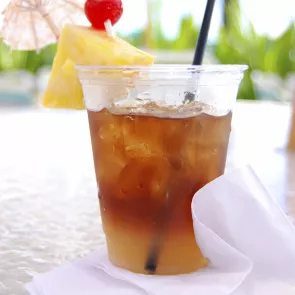 Glass of strawberry Mai Tai garnished with pineapple slice and cherry