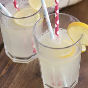 Two glasses of Weekenders' Punch garnished with lemon slices and a couple of strawss inside.