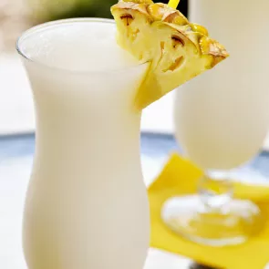 A glass of Apple Colada garnished with a slice of pineapple on a rim of glass