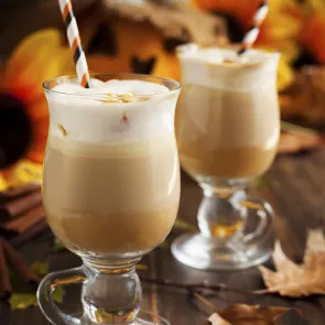 Two glasses of Boozy Pumpkin Milkshake topped with whipped cream and a straws