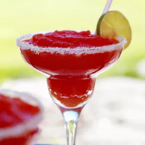 Rimmed glass of Cherry Margarita garnished with lime slice