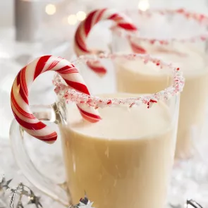 Mug of Choco-Peppermint Shake with candy cane garnished with a rim rimmed with milk and crushed candy cane.