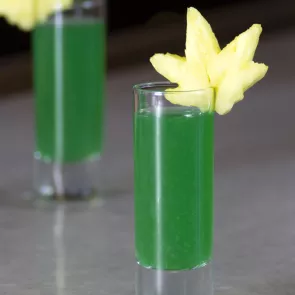 Two Glasses of Green Haze garnished with leaf shaped fruit