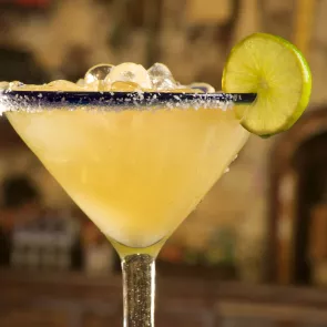 A glass of Nectarita, garnished with ice cubes, a wheel of lemon, and crushed sugar around the rim of the glass