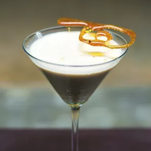 A glass of toffee drop martini garnished with spun sugar 