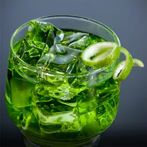 A cocktail glass of Green River garnished with a lime twist and some ice cubes.