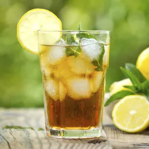 A glass filled with apple highball and lemon with mint