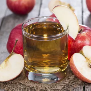 Glass of Apple 'n' Rye garnished with an apple slice, alongside some apples.