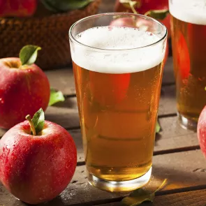 Glass of Beam® Applebees alongside two apples on a table.