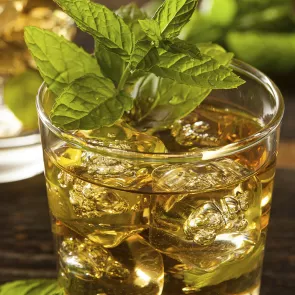 A glass of Dernier Cri garnished with mint leaves.