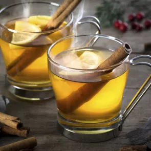 Two cups of Honey Toddy garnished with lemon wedge and cinnamon stick